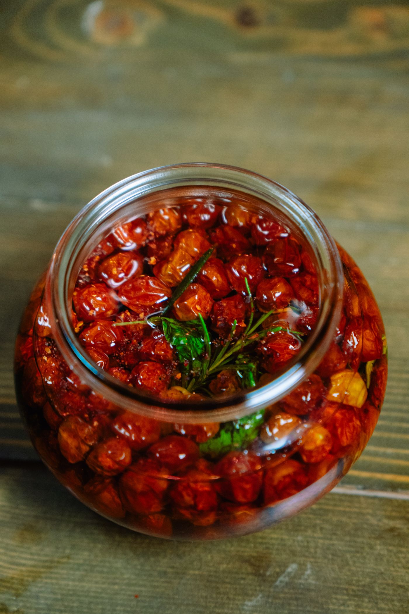 A jar of sun-dried tomatoes preserved in oil with herbs