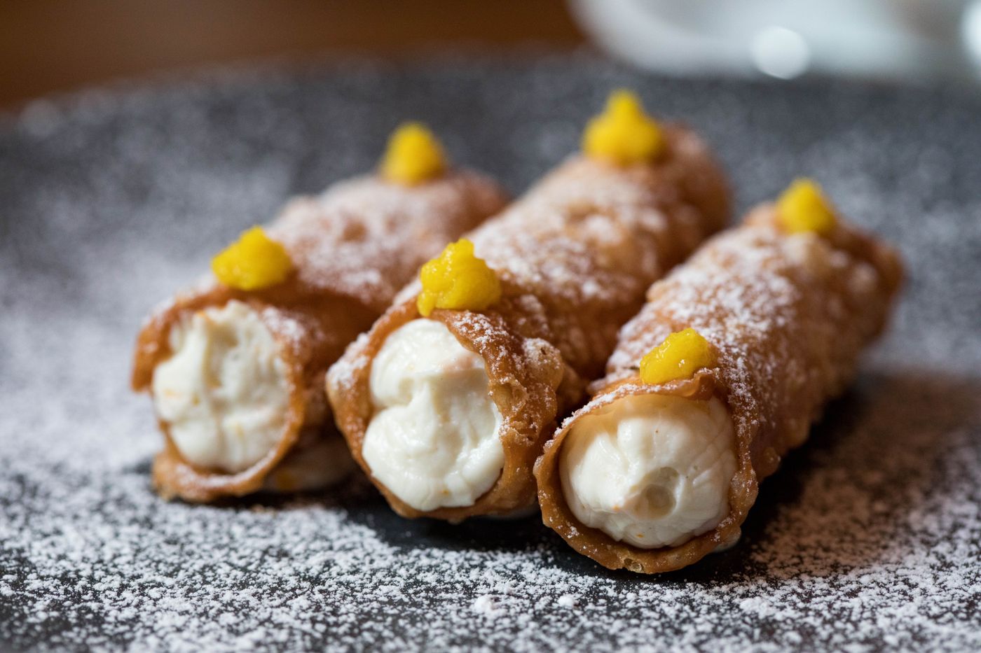 Three cannoli dusted with icing sugar