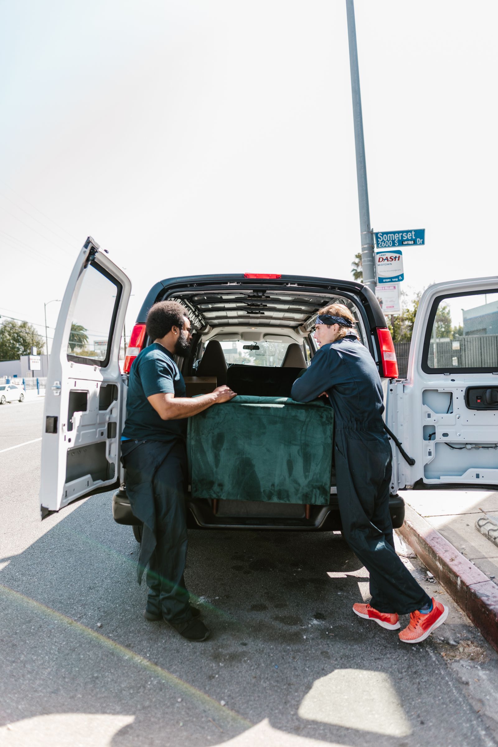 Two Northbound movers carefully loading a wrapped sofa into a van