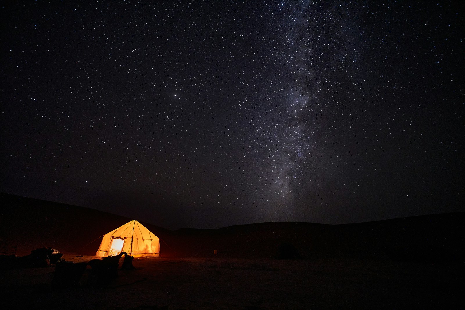 A small tent glowing under a sky full of stars